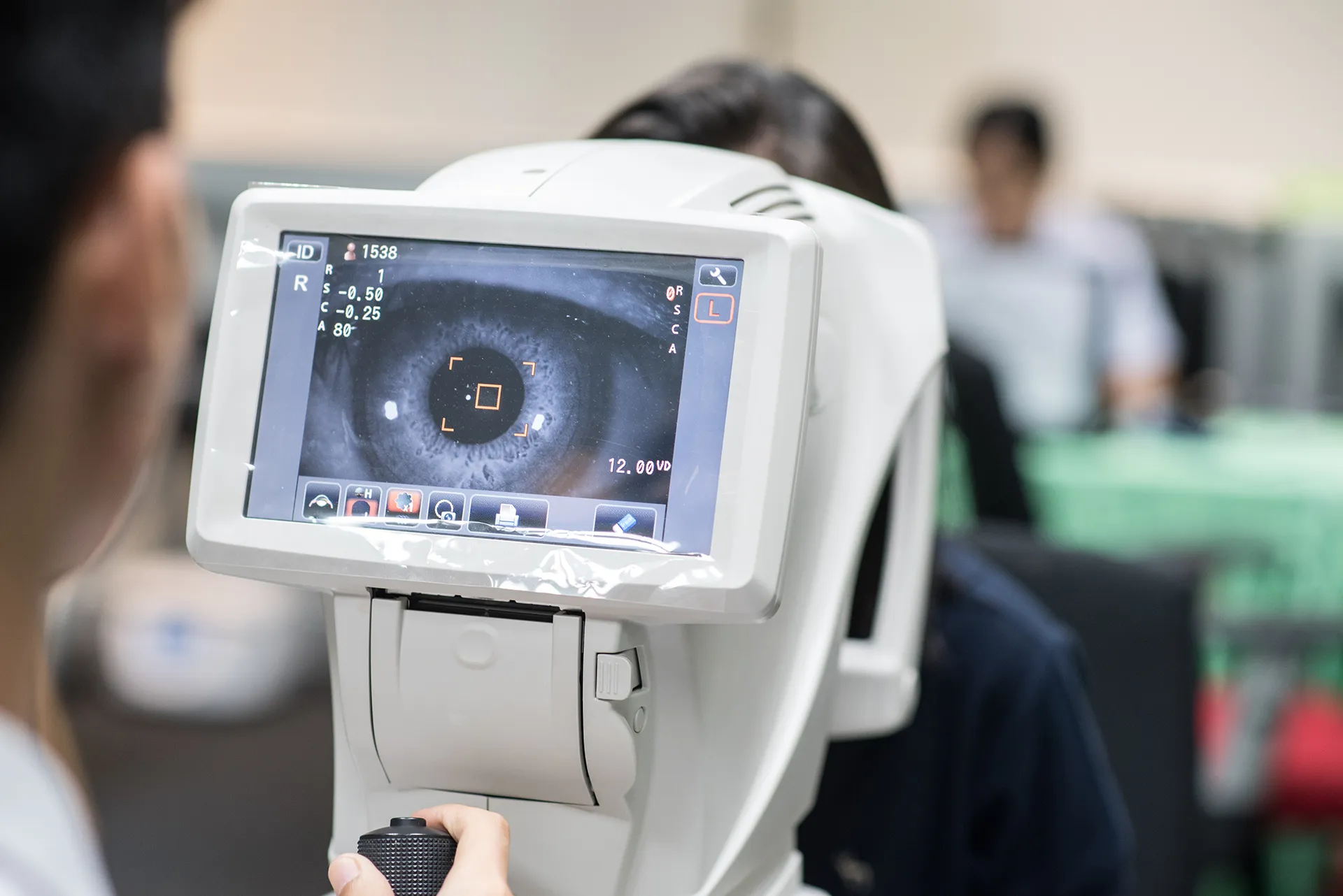 Doctor using a refractometer to examine a patient's eye during vision test